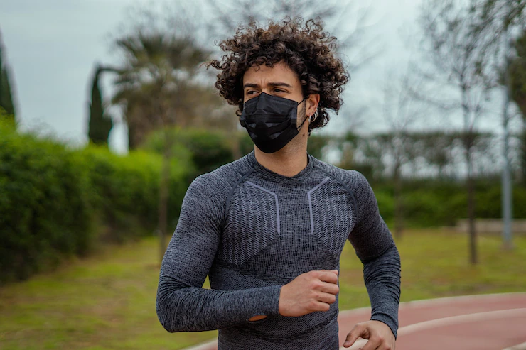 Closeup shot of a Caucasian young male running in the park wearing a mask