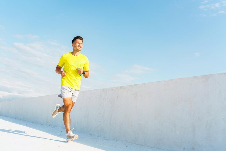 Man runs along a sunny white pathway with blue sky backdrop during a morning workout session