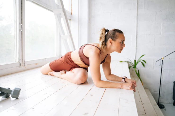 Flexible fit young woman with perfect athletic body wearing sportswear doing stretching exercises